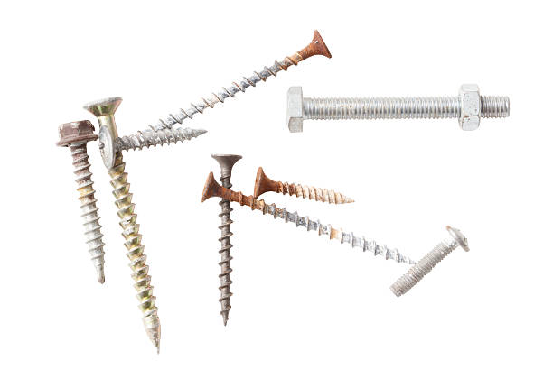 A bunch of different sized screws and nails are scattered on a white background. The screws and nails are of various sizes and shapes, with some being larger and others smaller