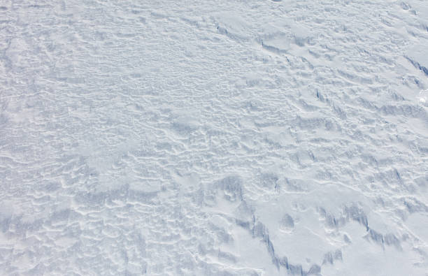 A snow covered ground with a few small snowflakes. The snow is white and the ground is covered in it