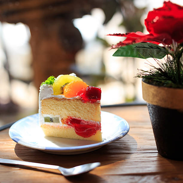 istock Colorful Fruit Cake Slice on Plate with Bright Green Plant in Background 2206956415