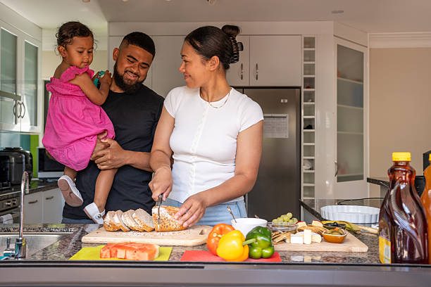 A young Pacific Island family prepares lunch together in their home kitchen.