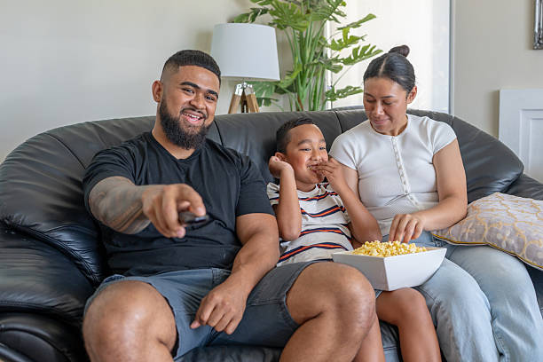 Pacific Islander Family Watching TV and Eating Popcorn on Couch