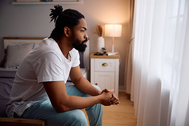istock Thoughtful black man sitting on a bed. 2206958971