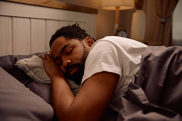 istock African American man sleeping in his bed at night. 2206959055