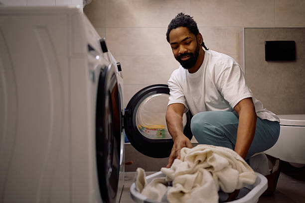 istock Happy black man doing laundry at home 2206959415