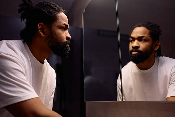 istock Black man looking himself in a mirror in the bathroom. 2206959614