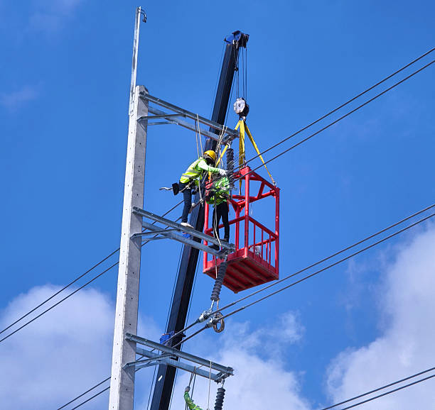 istock Men in work clothes and hard hats are installing high-voltage wires on a power pole 2206959755