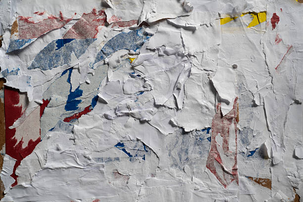 istock Dirty wall texture with peeled white, red, blue and yellow paper 2206961646