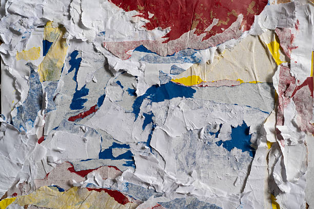 istock Dirty wall texture with peeled white, red, blue and yellow paper 2206961648