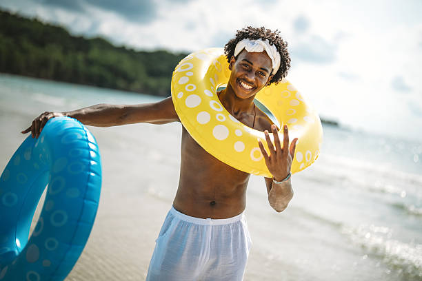 istock Young Black man enjoying a sunny beach day, running through ocean waves, smiling and feeling free 2206964250