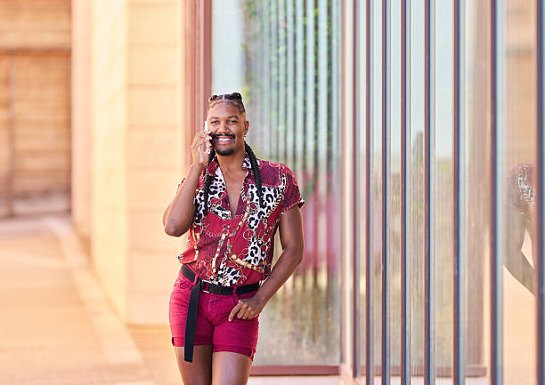 istock Stylish androgynous man talking on smartphone while walking down street 2206964404