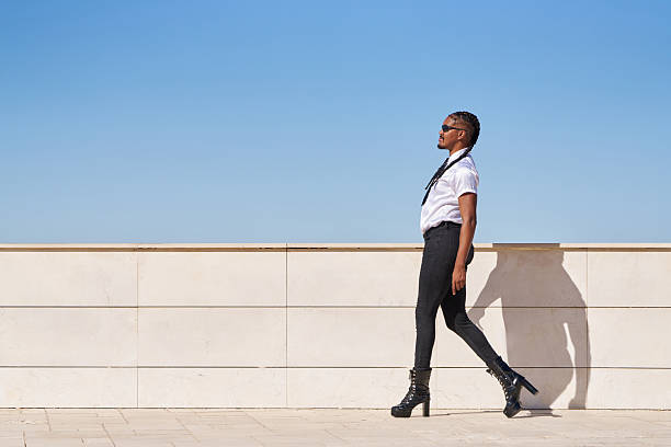 istock Stylish androgynous man walking on a terrace on a sunny day 2206964415
