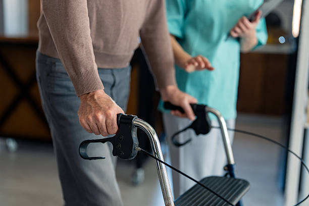 istock Professional Physical Therapist Assists Senior Patient With Walker Training 2206964795