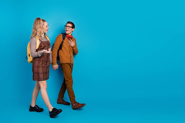 istock Young couple walking and holding hands, smiling against a vibrant blue background while wearing casual retro-style outfits 2206966646