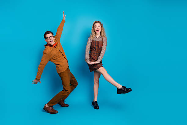 istock Energetic young couple posing enthusiastically against a bright blue background, showcasing retro fashion and a playful mood 2206966700