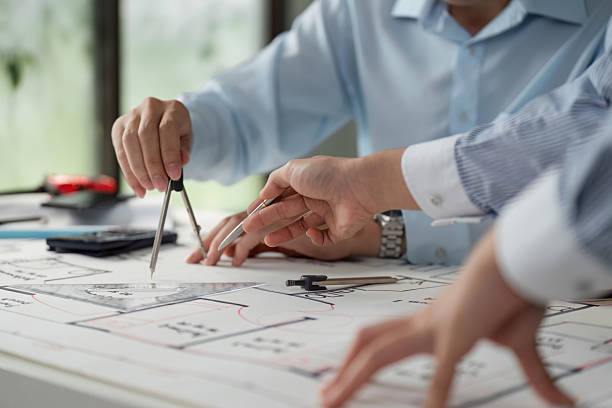 istock Architectural Collaboration and Planning. Close-up of professionals actively discussing architectural designs over detailed blueprints. 2206972777
