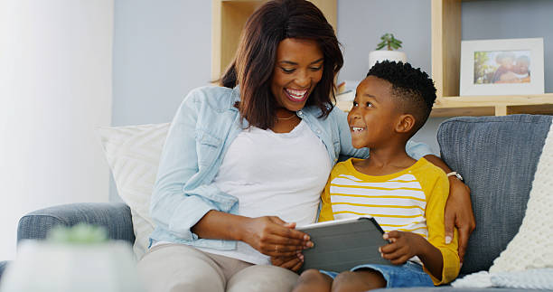 istock Tablet, relax or mother with kid on sofa playing, educational game or online for learning. Happy, bonding or mom with boy child on digital technology for entertainment in living room in home together 2206972865