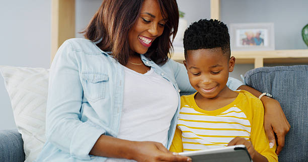 istock Tablet, relax and mom with kid on sofa playing educational game online for learning. Happy, bonding and mother with boy child on digital technology for entertainment in living room in home together. 2206972868