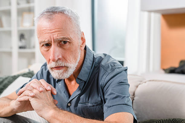 istock Thoughtful Older Man Sitting on a Sofa in a Cozy Living Room 2206974390
