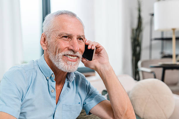 istock Smiling Senior Man Talking on Smartphone While Sitting at Home 2206974413