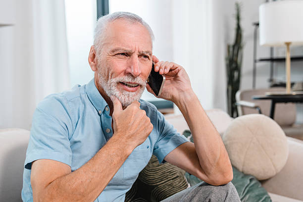 istock Senior Man Talking on Smartphone While Relaxing in a Comfortable Living Room 2206974419
