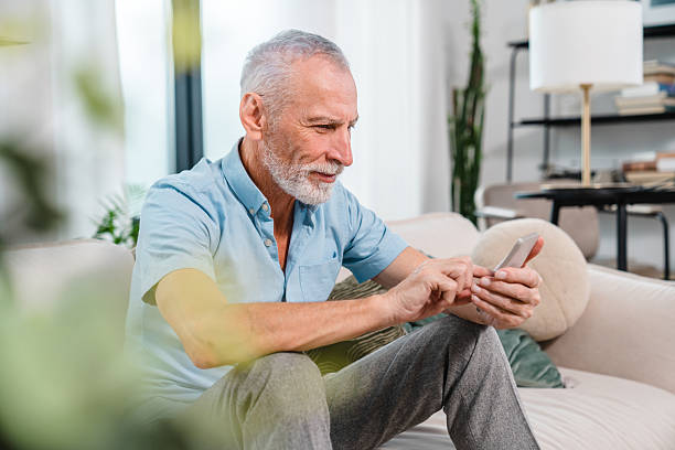 istock Senior Man Using Smartphone While Relaxing on a Cozy Couch at Home 2206974438
