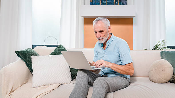 istock Senior Man Working on Laptop at Home in Casual Setting 2206974483