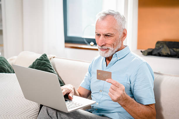 istock Smiling Senior Man Shopping Online Using Laptop and Credit Card 2206974531