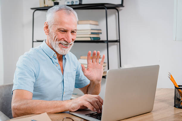 istock Senior Man Smiling During a Video Call on His Laptop in a Cozy Room 2206974721