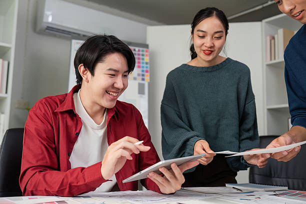 istock Engaging Teamwork in Design Concepts. Group members discussing and reviewing design ideas while smiling and collaborating. 2206974733