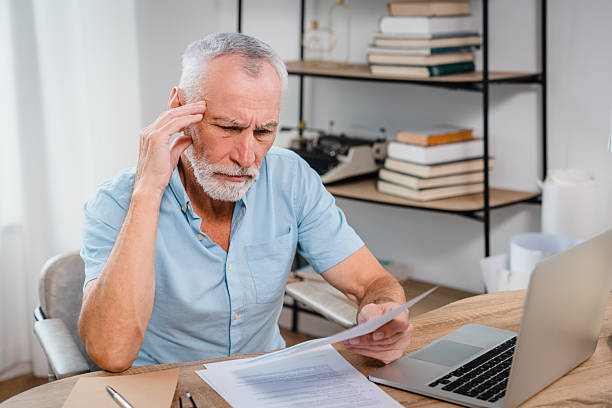 istock Senior Man Reviewing Important Documents at Desk With Thoughtful Expression 2206974760