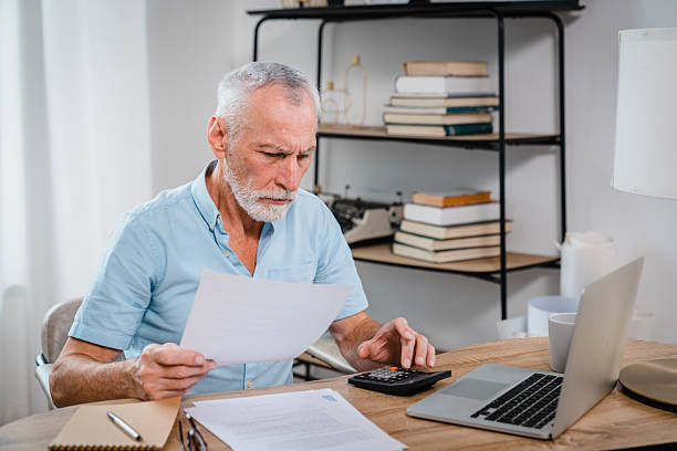 istock Elderly Man Reviewing Finances with Laptop and Documents at Home Office 2206974764