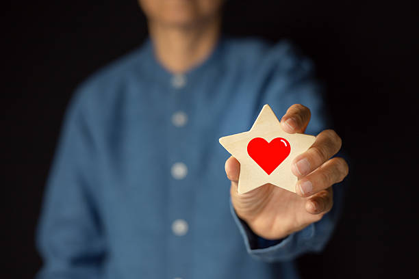 Concept of positive emotions. A man holds a star shape and a red heart inside. Positive thinking, Satisfaction Rating and reviews, recommendations.