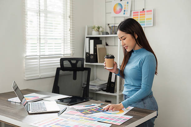 istock Creative Decision Making and Coffee Break. A designer smiles while reviewing color palettes and holding a coffee cup. 2206977878