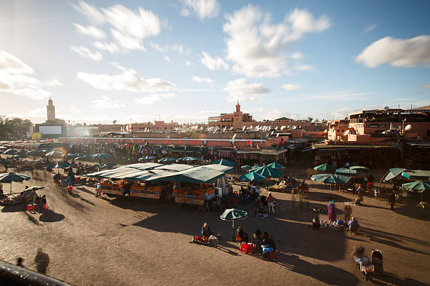 The heart of Marrakech at dusk—Djemaa el-Fna Square comes alive with food stalls, merchants, and a bustling crowd, with the famous Koutoubia Mosque standing tall in the background.