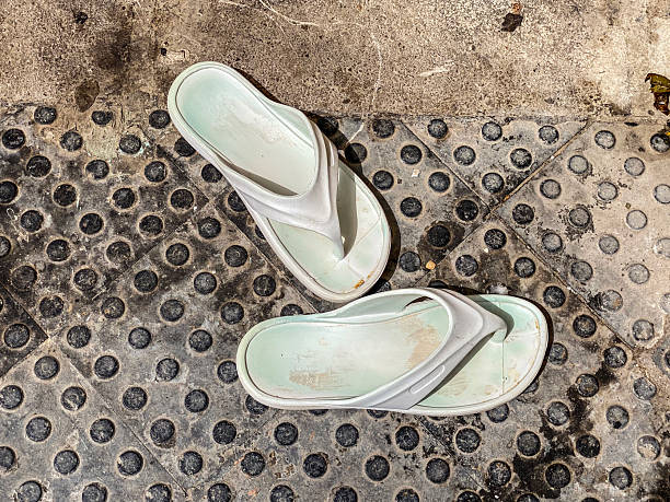 Green flip flops with polka dots and pink stripes on the white background