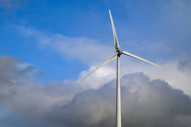 Wind turbine producing sustainable electricity  with a cloudy stormy sky in the background.