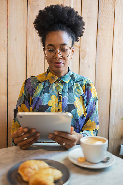 istock Woman enjoying coffee while reading on a tablet in a cozy cafe 2206986599