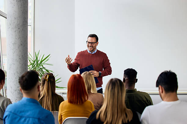 Confident Speaker Addressing a Diverse Group in a Modern Classroom Setting stock photo