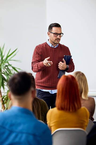 istock Man Giving Presentation to Group of Attendees in a Bright Modern Room 2206986657