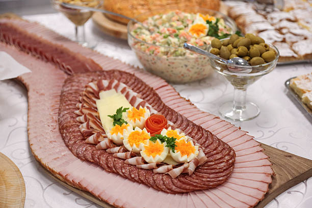 Tables are filled with an array of colorful dishes featuring meats, salads, and various breads, all beautifully presented for a festive celebration with guests enjoying the meal.