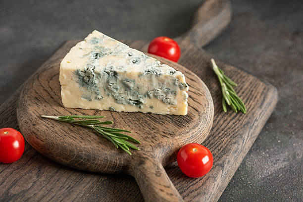 istock Blue cheese with rosemary and cherry tomatoes on a wooden cutting board, selective focus 2206990375