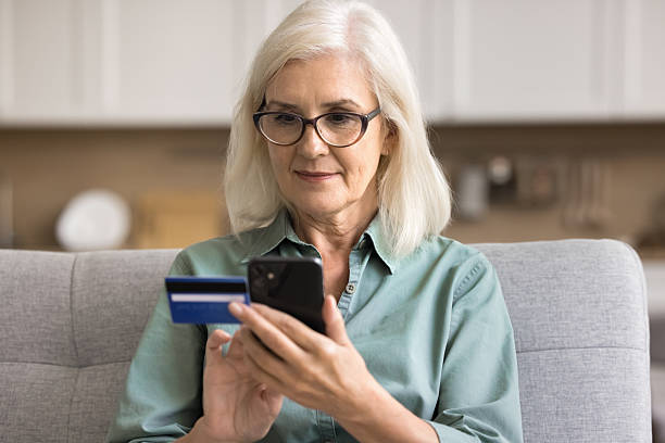 istock Female sit on sofa at home holding card and cellphone 2206990480