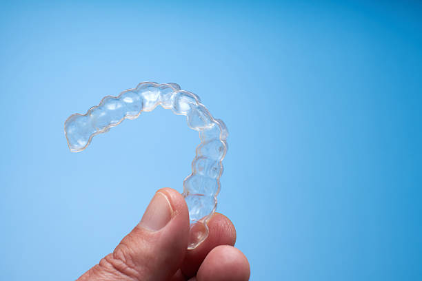 istock Clear Dental Aligner Held in Hand Against Blue Background 2206990713