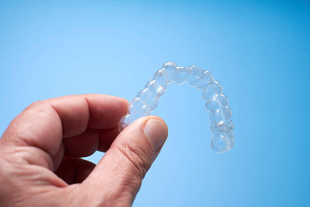 istock Clear Dental Aligner Held in Hand Against Blue Background 2206990716