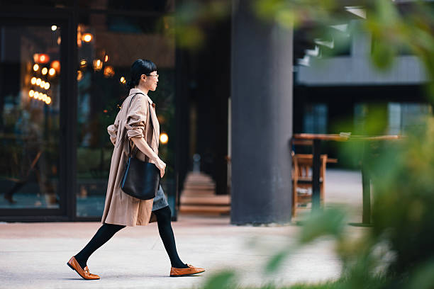 スタイリッシュなアクセサリーで都会の環境を自信を持って歩くビジネスウーマン - 歩く ストックフォトと画像