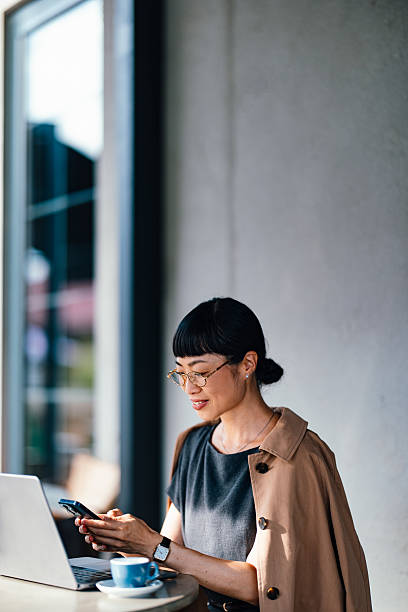istock Businesswoman Using Smartphone at Cafe Table with Laptop and Coffee 2206992595