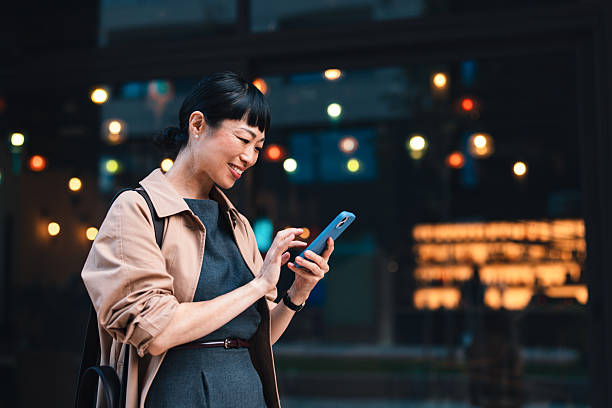 istock Smiling Businesswoman Browsing Smartphone Outdoors in Urban Evening Setting 2206992681
