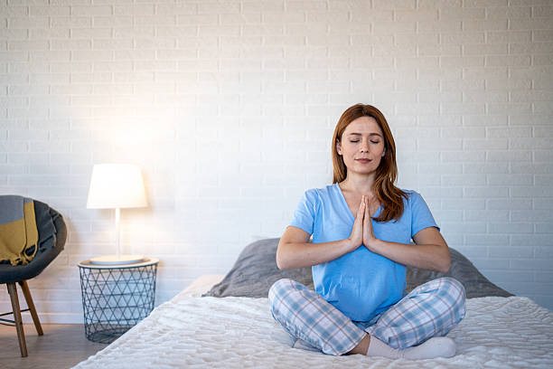 istock Serene woman meditating on bed in pajamas: finding inner peace 2207000070