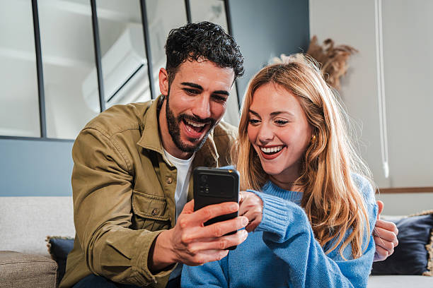 istock Joyful couple sharing delightful moments while using a smartphone to explore fun applications and exciting content together in a cozy home atmosphere filled with laughter and connection 2207001117