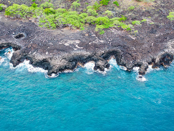 View of molten lava flowing into crashing Pacific waves as seen in Hawaii Volcanoes National Park.